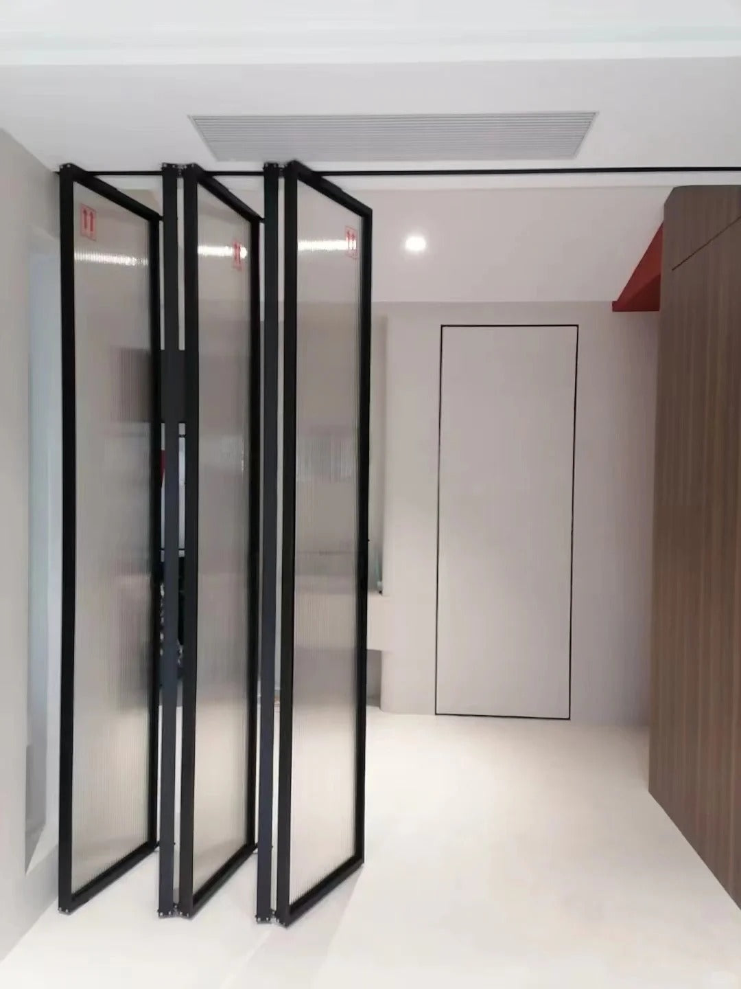 Rothnow Aluminum 16x45 Series Slim Frame Bi-fold Folding Door with clear glass in black finish, white frame, and slim profile.