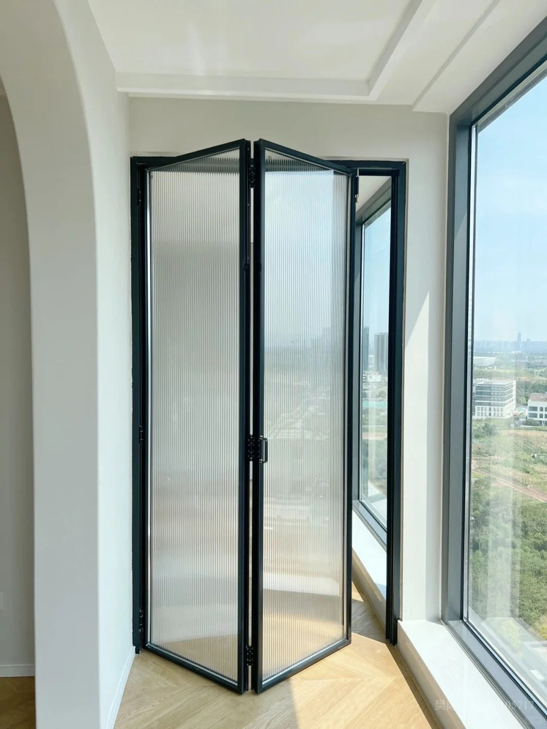 Rothnow® aluminum 16x45 series slim frame bi-fold door with waved glass, white finish, and clear glass panels.