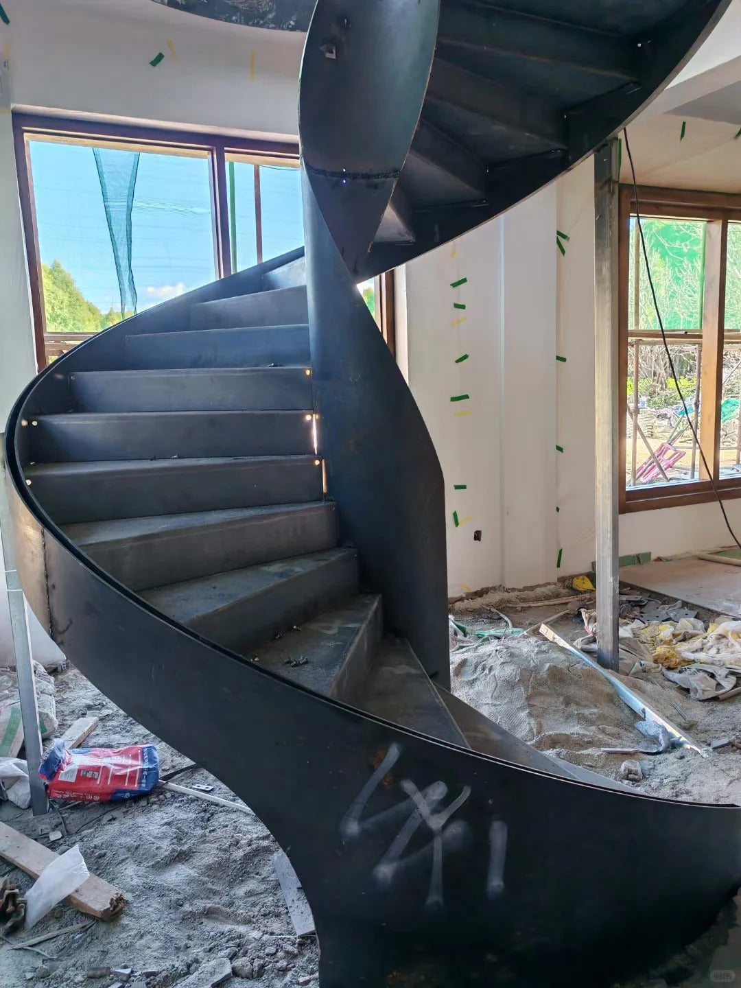 Black Rothnow Spiral Staircase RNSS05 art-style staircase with sleek, curved metal steps and modern design, installed indoors.